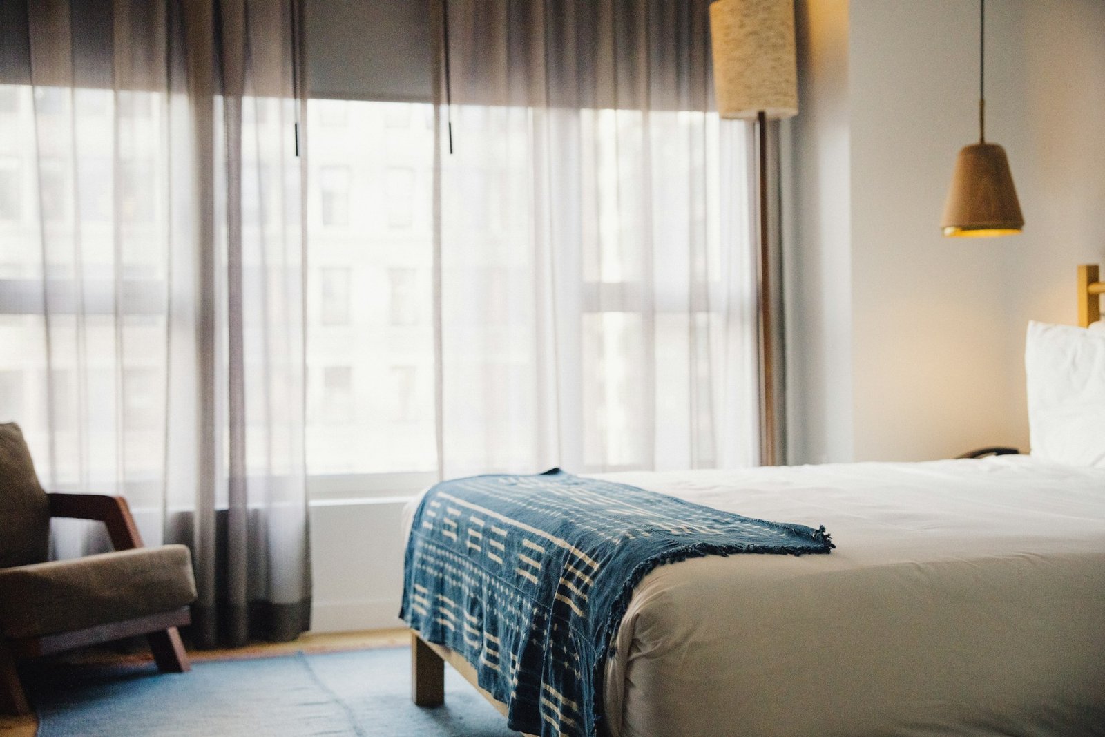 A hotel bedroom with a bed, chair and window.