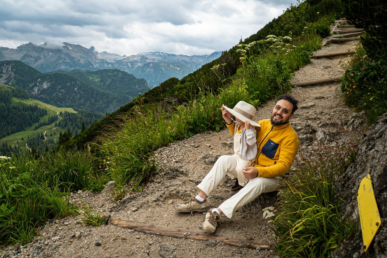 A father and child resting on a mountain path near Konigssee in Germany.