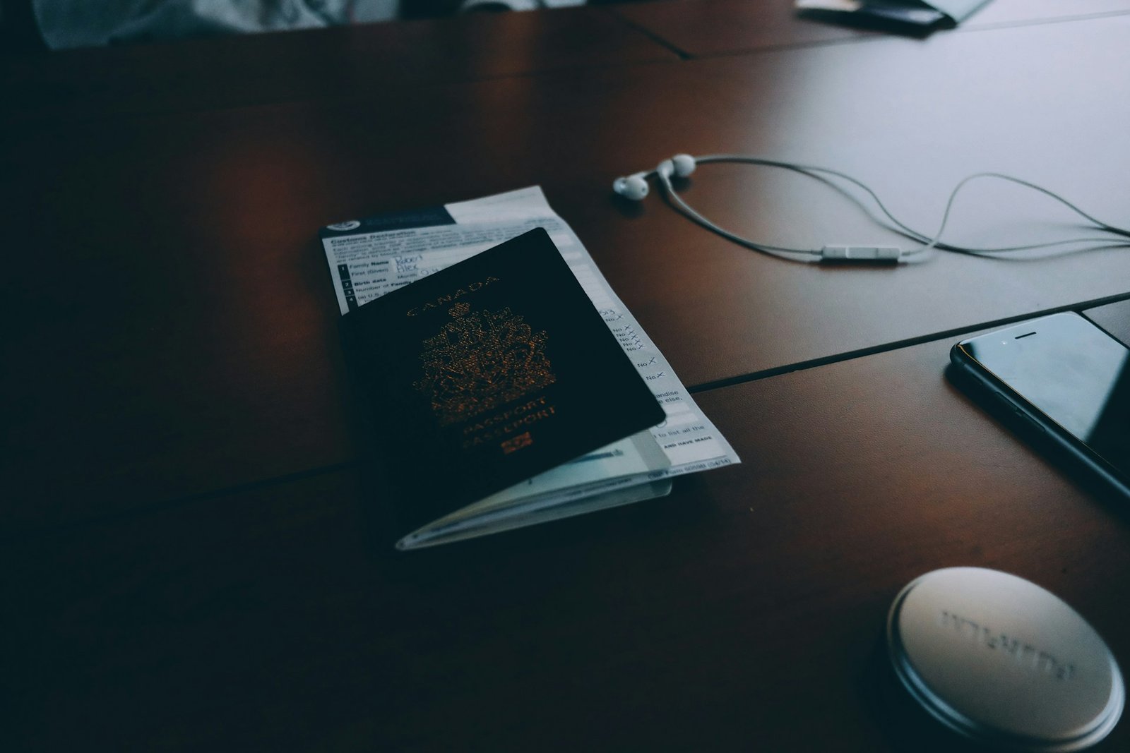 A closed passport and travel items on a desk.