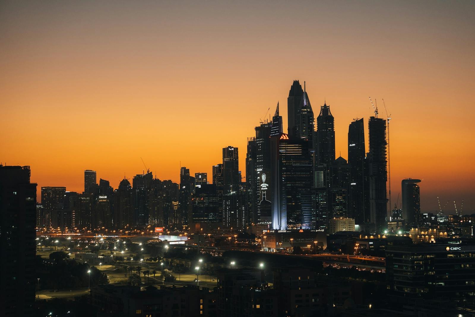Dubai's skyline against an orange sky at sunset.