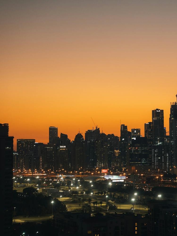 Dubai’s skyline against an orange sky at sunset.